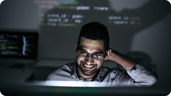 Smiling software developer looking on script on computer screen. 
